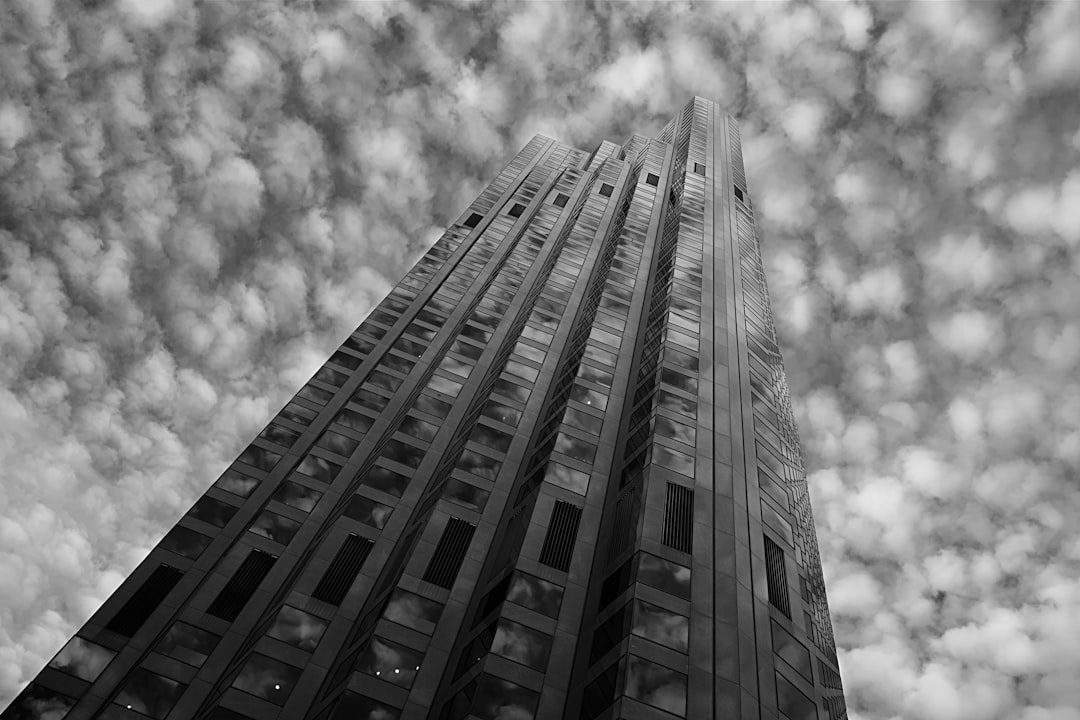 grayscale low-angle photo of high-rise building under cloudy sky