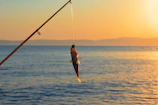 A proud fisherman holding a large red snapper against a backdrop of calm Florida waters at sunset.