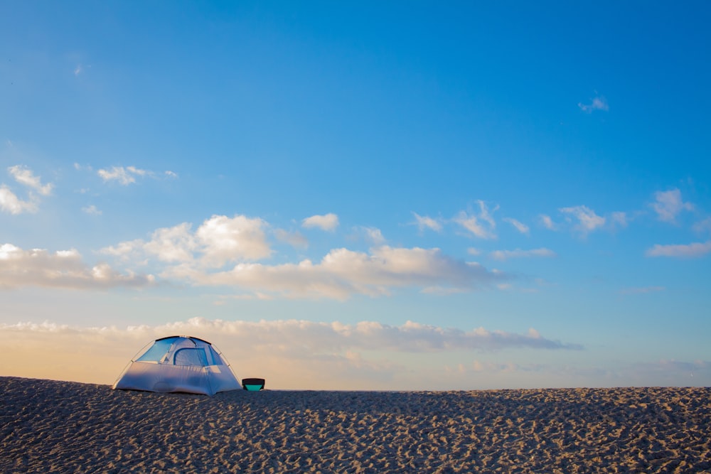 tent on sand under blue sky and white clouds