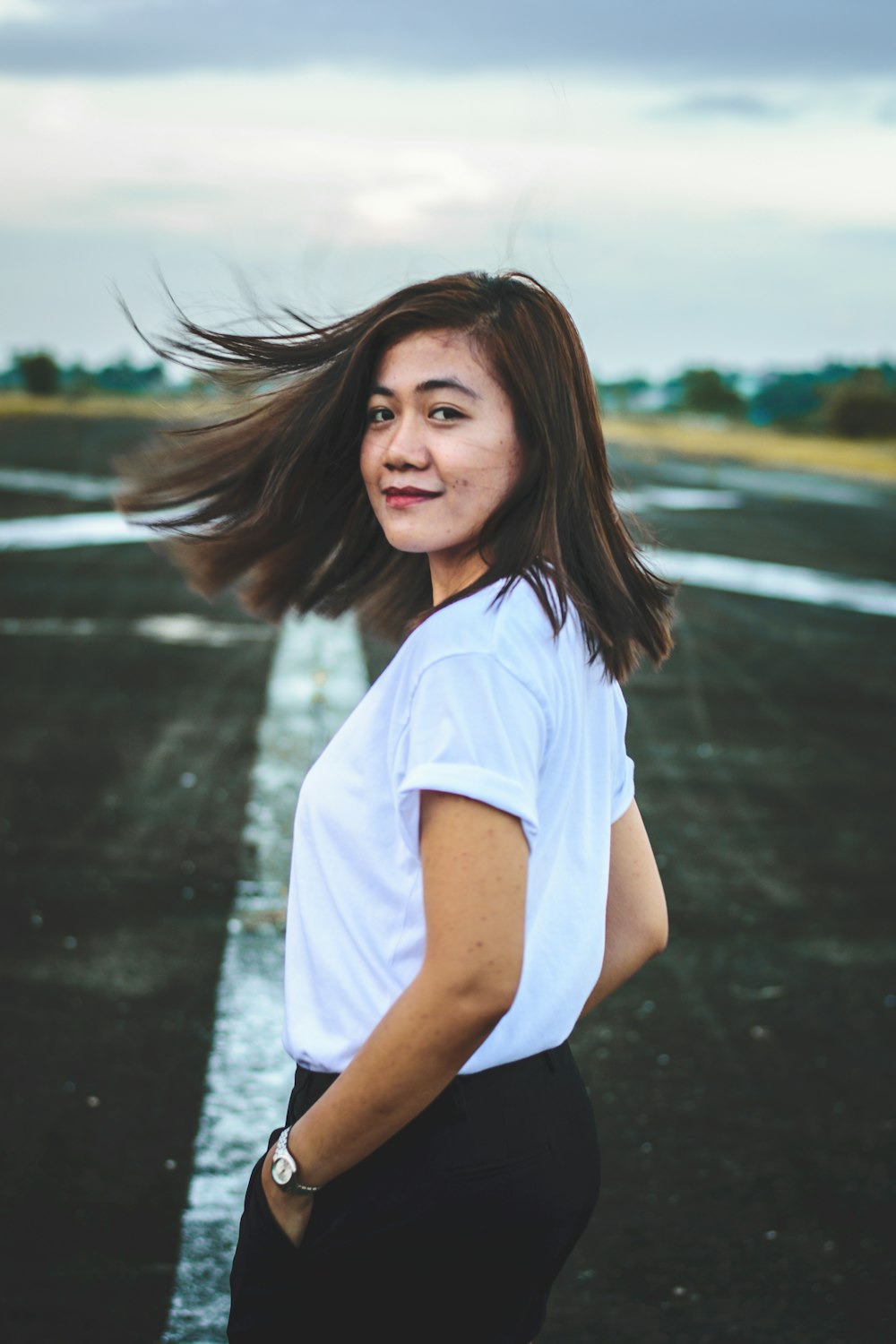 smiling woman standing on concrete floor in white t-shirt