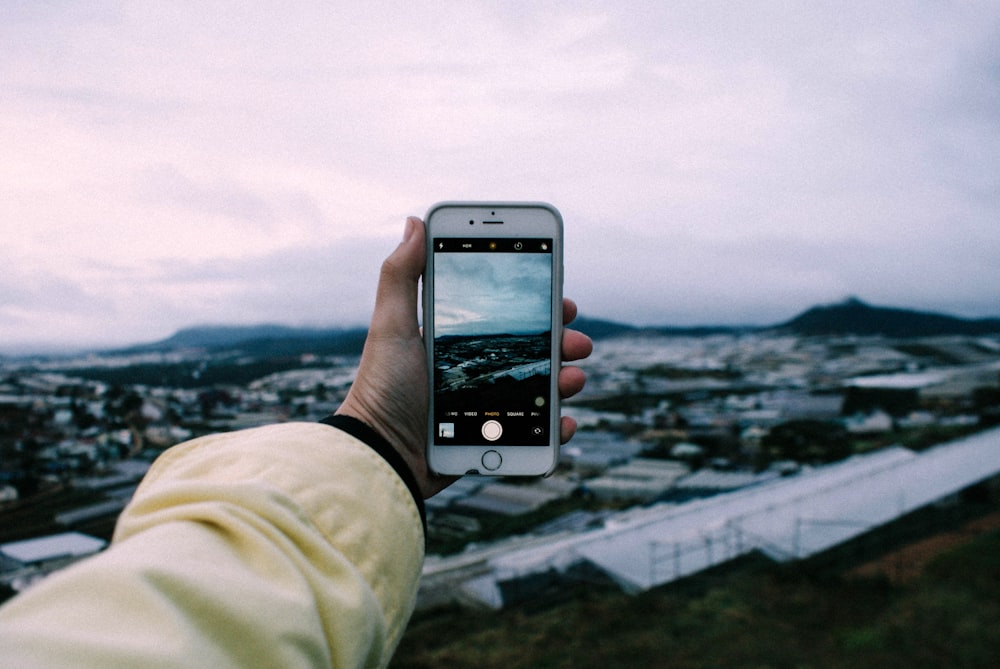 person holding silver iPhone 6 taking photo of city buildings