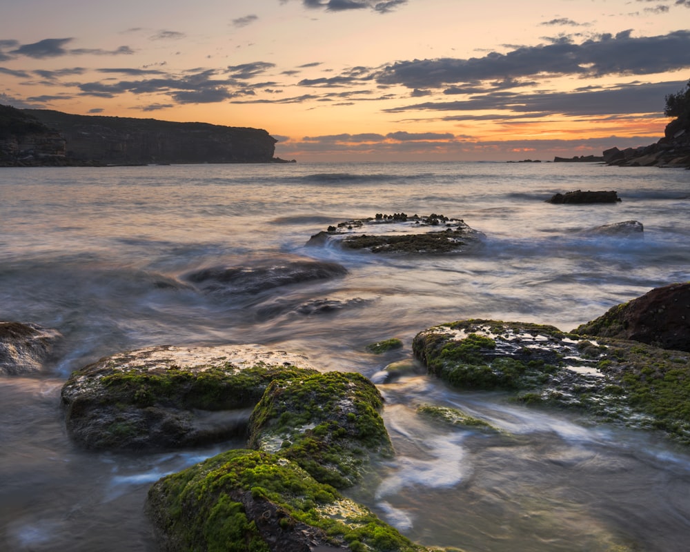 rocks on beach under nimbus clouds