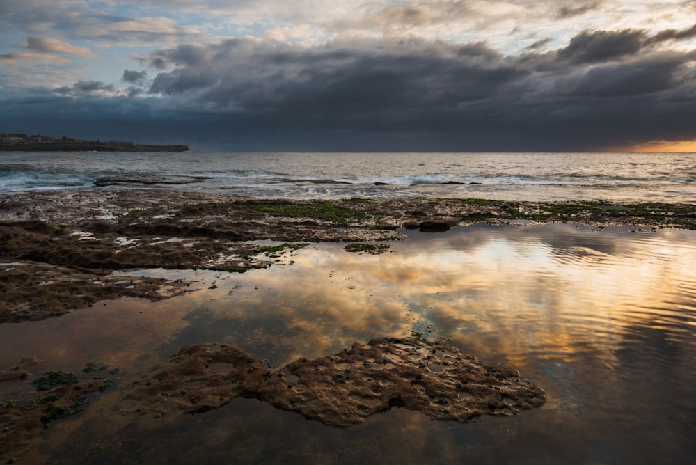 calm body of water under grey sky