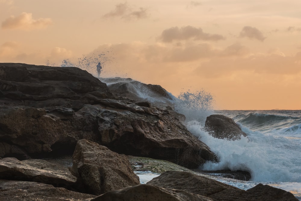 Photographie en accéléré de vagues éclaboussant sur les rochers pendant la journée