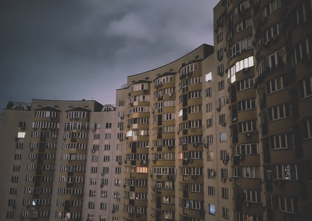 concrete high-rise building under cloudy sky during nighttime