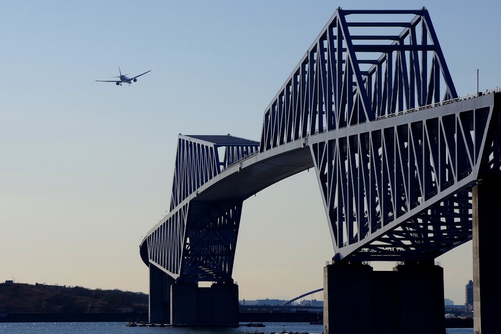 plane near bridge under clear blue sky