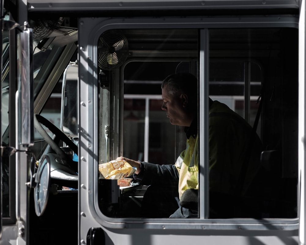 man sitting on vehicle's driver's seat holding pack of snack