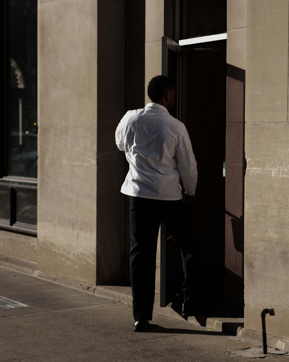 man wearing dress shirt standing beside door