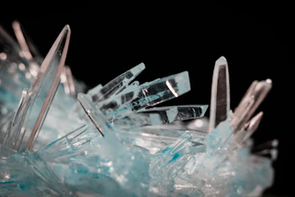 A cluster of sparkling natural zircons in various shades of blue and white, arranged elegantly on a reflective surface.