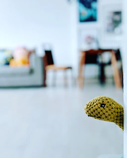 Mischievous creature peeking from behind a living room couch with a virtual weapon