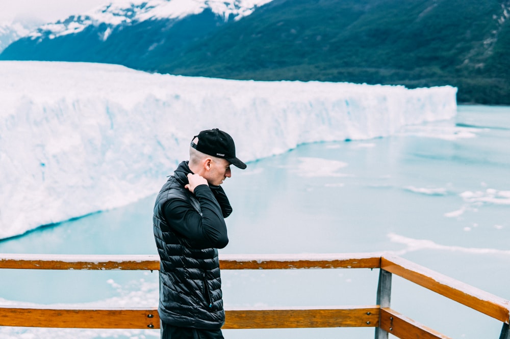 man in black jacket standing near iceberg