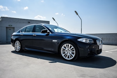 A sleek silver sedan parked near India Gate under a clear blue sky.