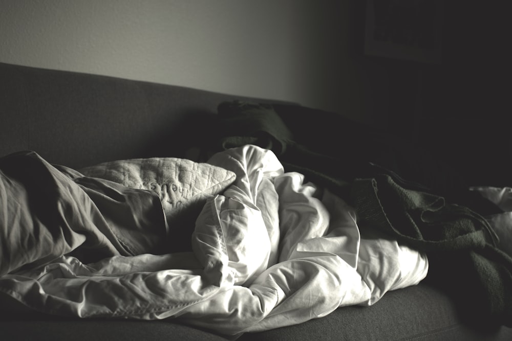 Fotografía en escala de grises de mantas arrugadas en el sofá