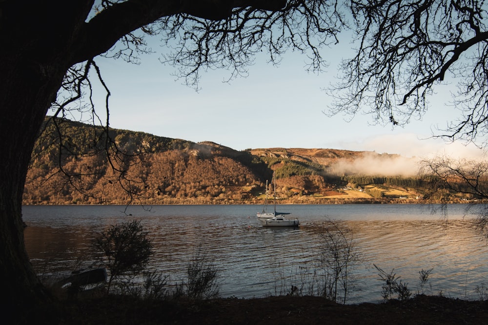 landscape photography of boat floating on body of water surrounded by mountains