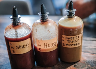 three filled condiment shakers on brown wooden surface