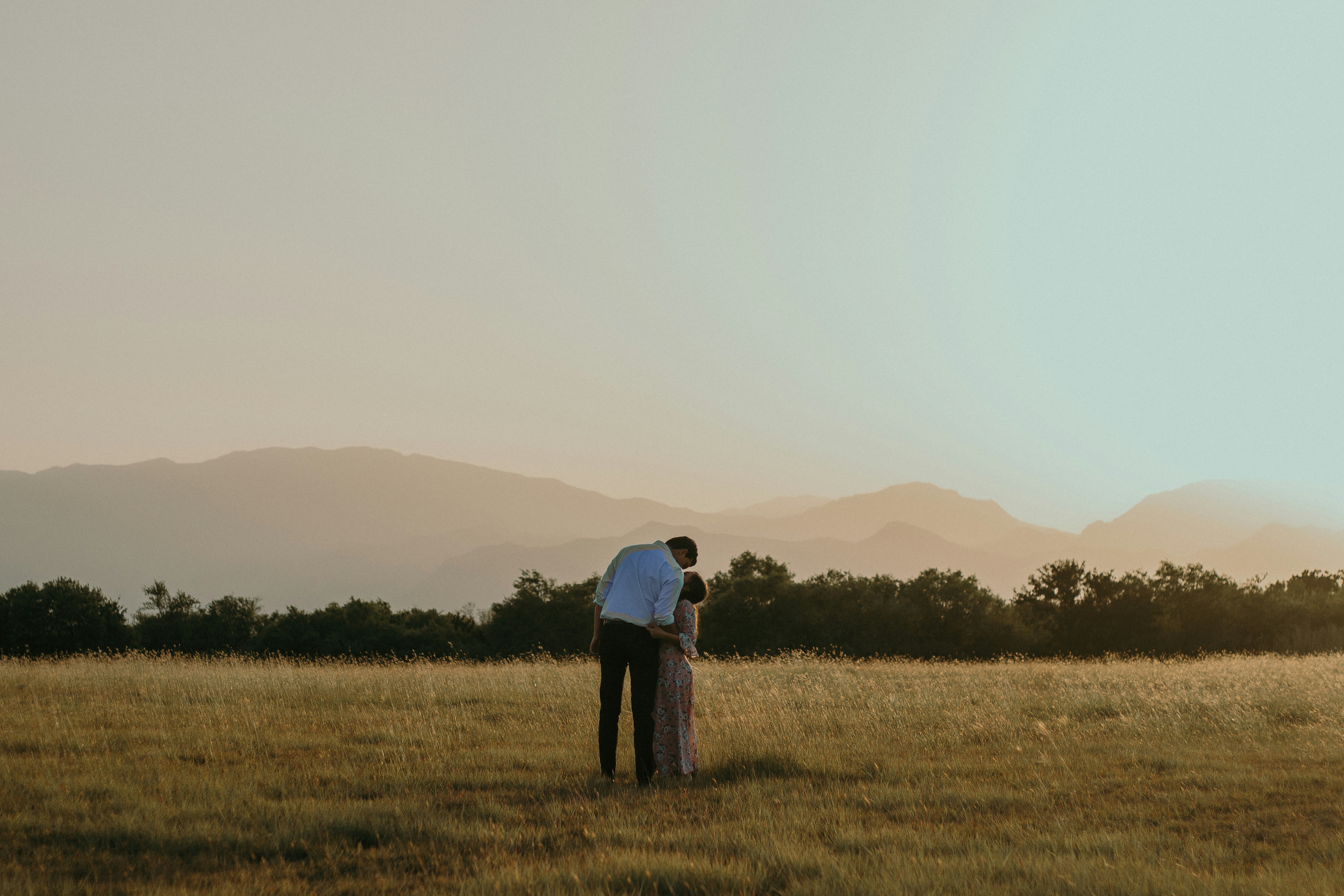 man and woman kissing in middle of plaid field during daytime