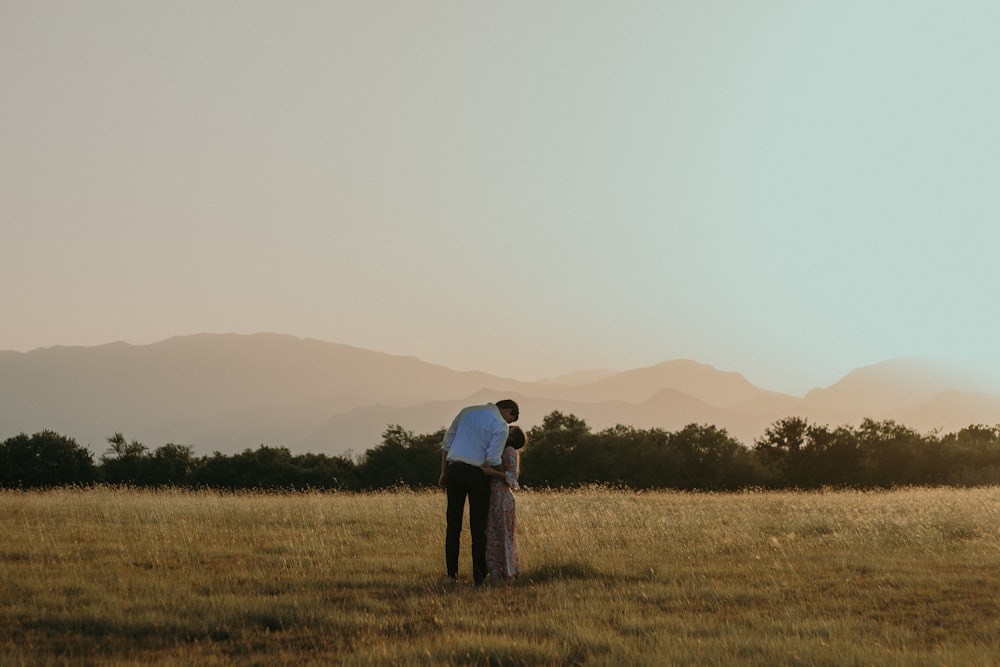 man and woman kissing in middle of plaid field during daytime