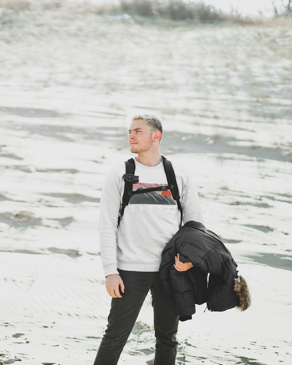 man standing near the body of water holding jacket during daytime