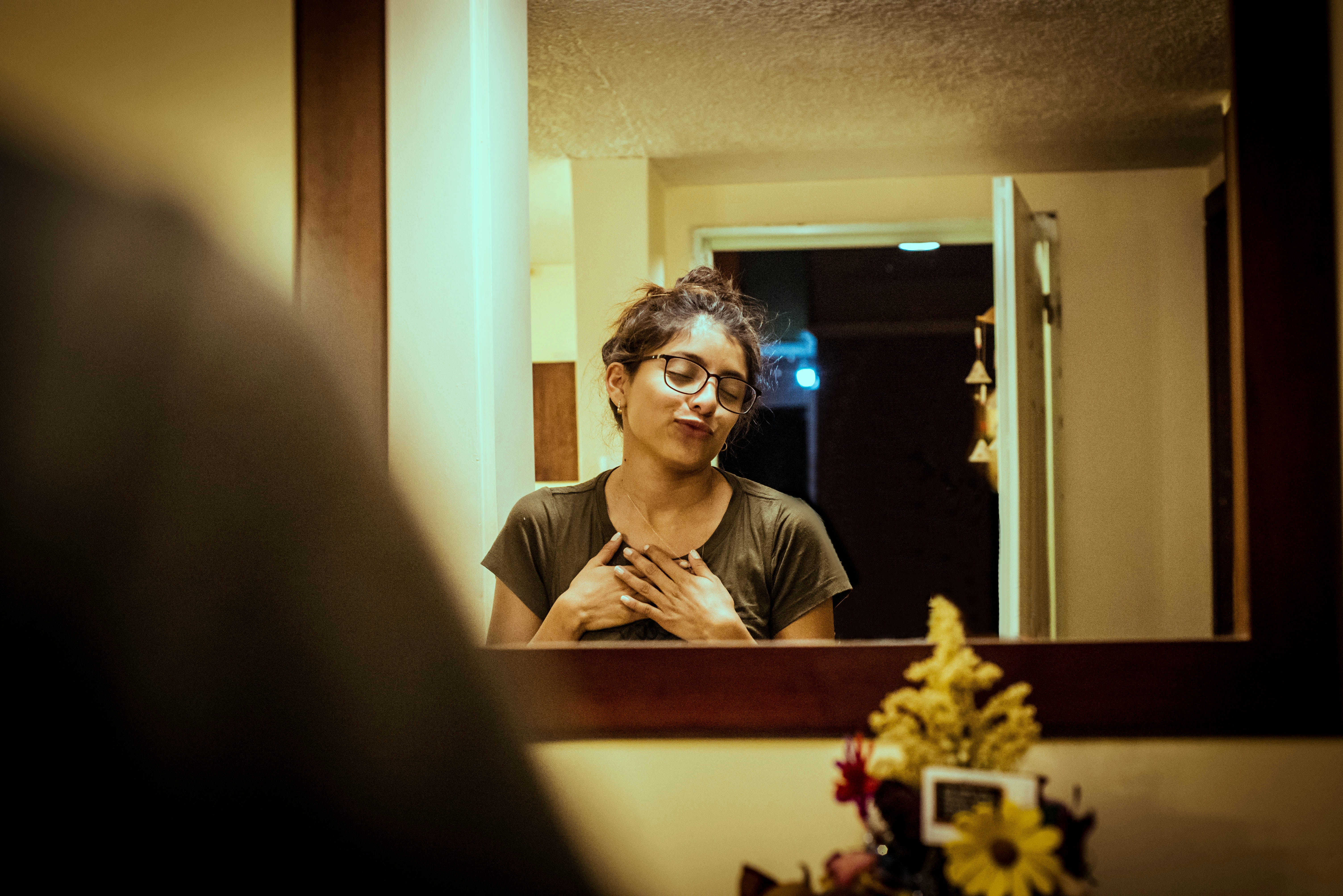 woman in gray shirt standing in front of wall mirror
