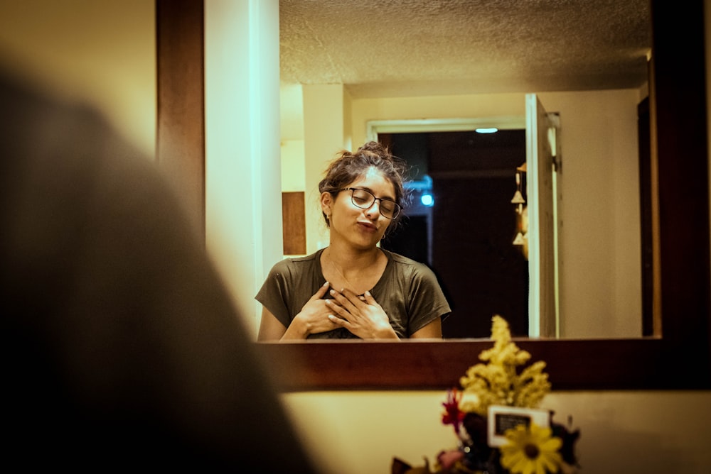 woman in gray shirt standing in front of wall mirror