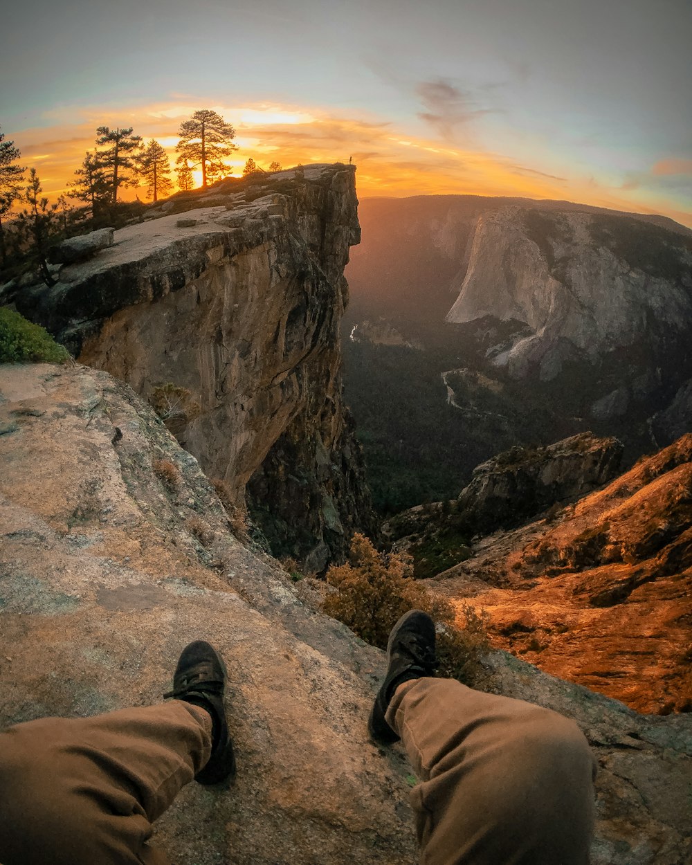 person pair of shoes and sitting on edge of mountain