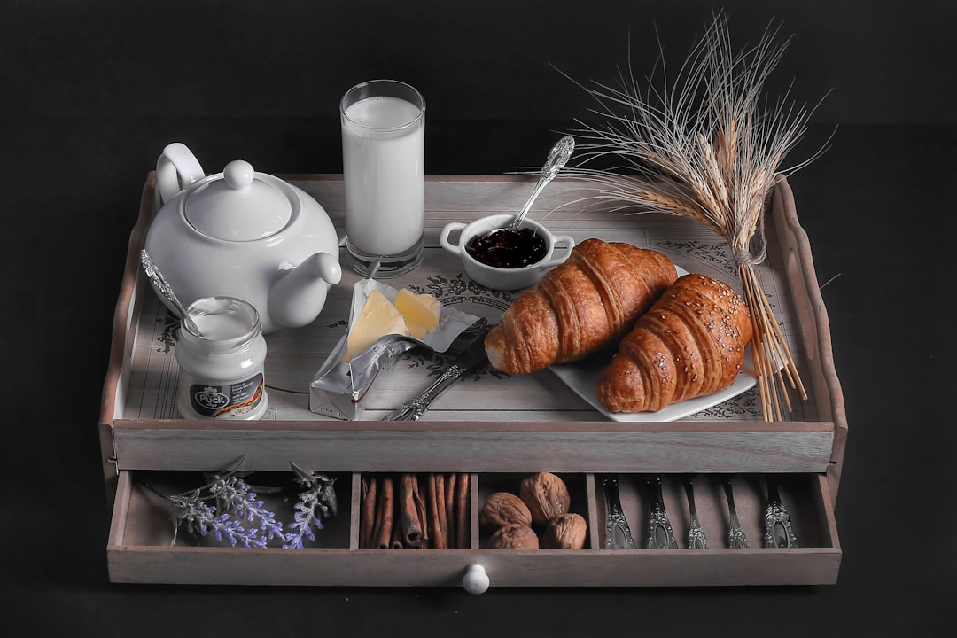 croissant bread beside glass of milk on wooden tray