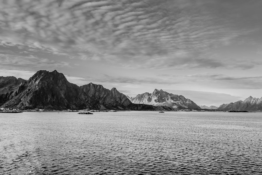 grayscale photography of rocky mountain under cloudy sky