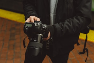 man in black jacket holding DSLR camera