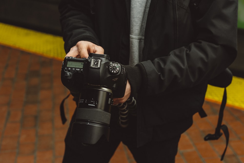 man in black jacket holding DSLR camera