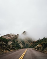 A winding mountain trail disappearing into a misty horizon under soft dawn light.