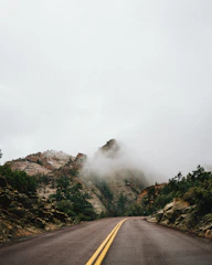 A cinematic frame from a video showing a winding road through misty mountains.