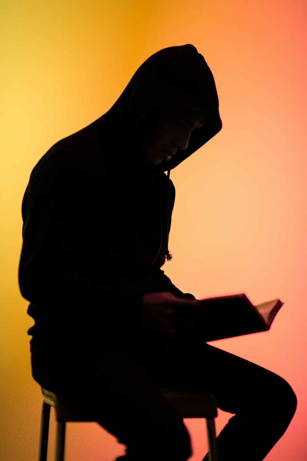 man reading book while sitting on chair