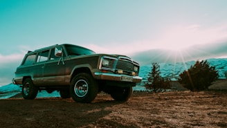 SUV driving on a dirt road with a scenic sunset background.