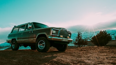 SUV driving on a dirt road with a scenic sunset background.