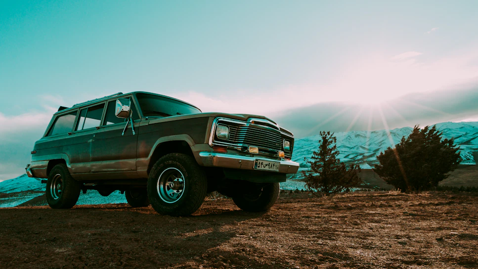 A shiny red SUV parked against a scenic mountain backdrop during golden hour.