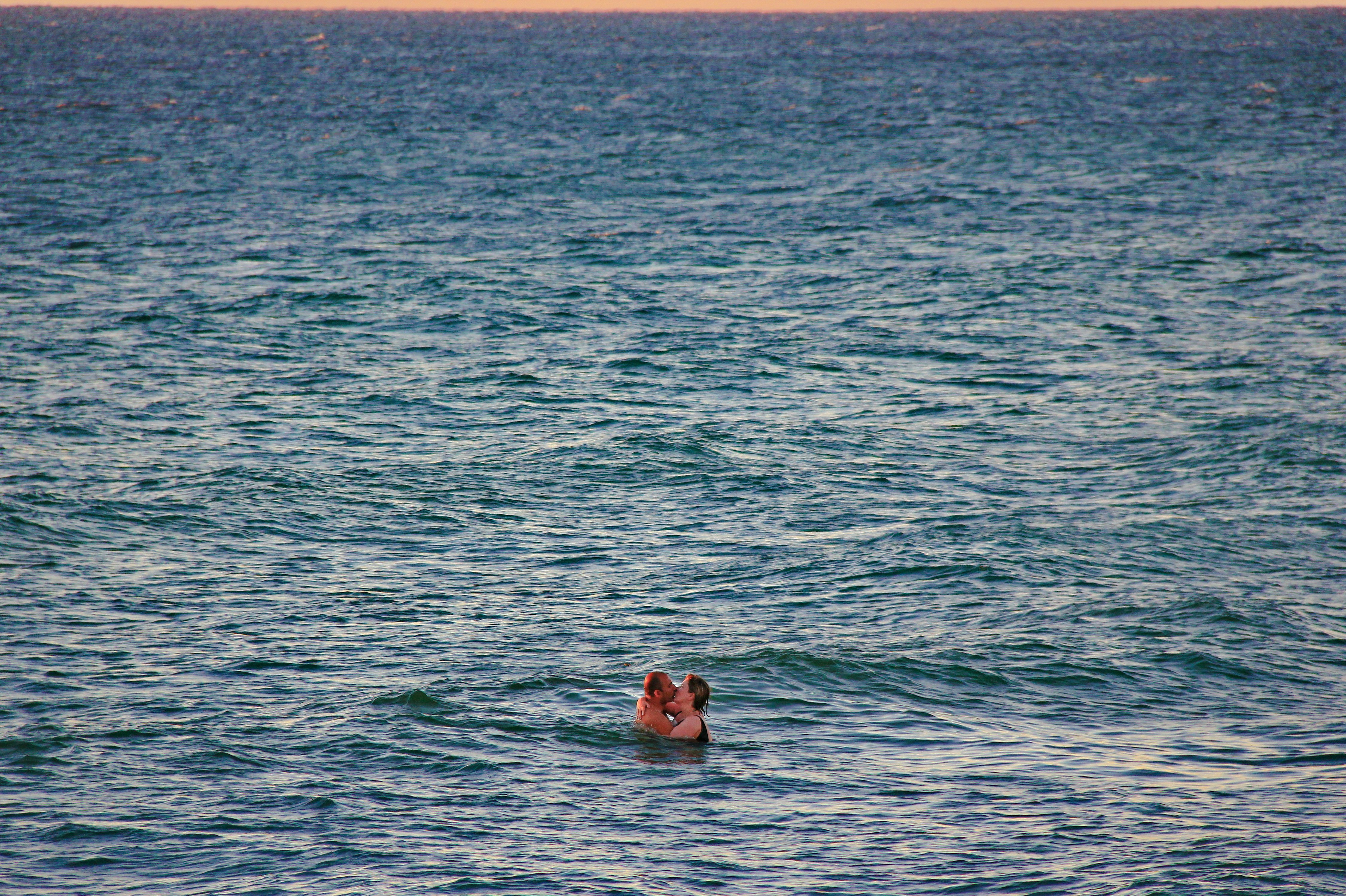 man and woman kissing on sea