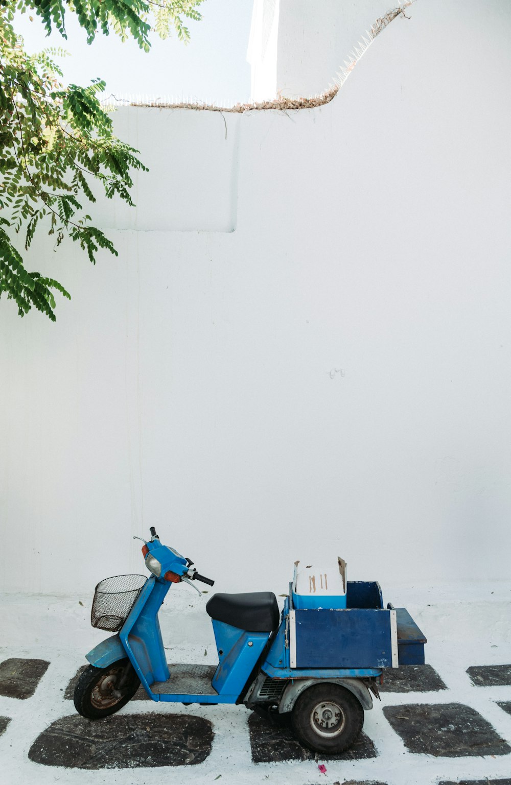 blue and black minibike beside white painted wall