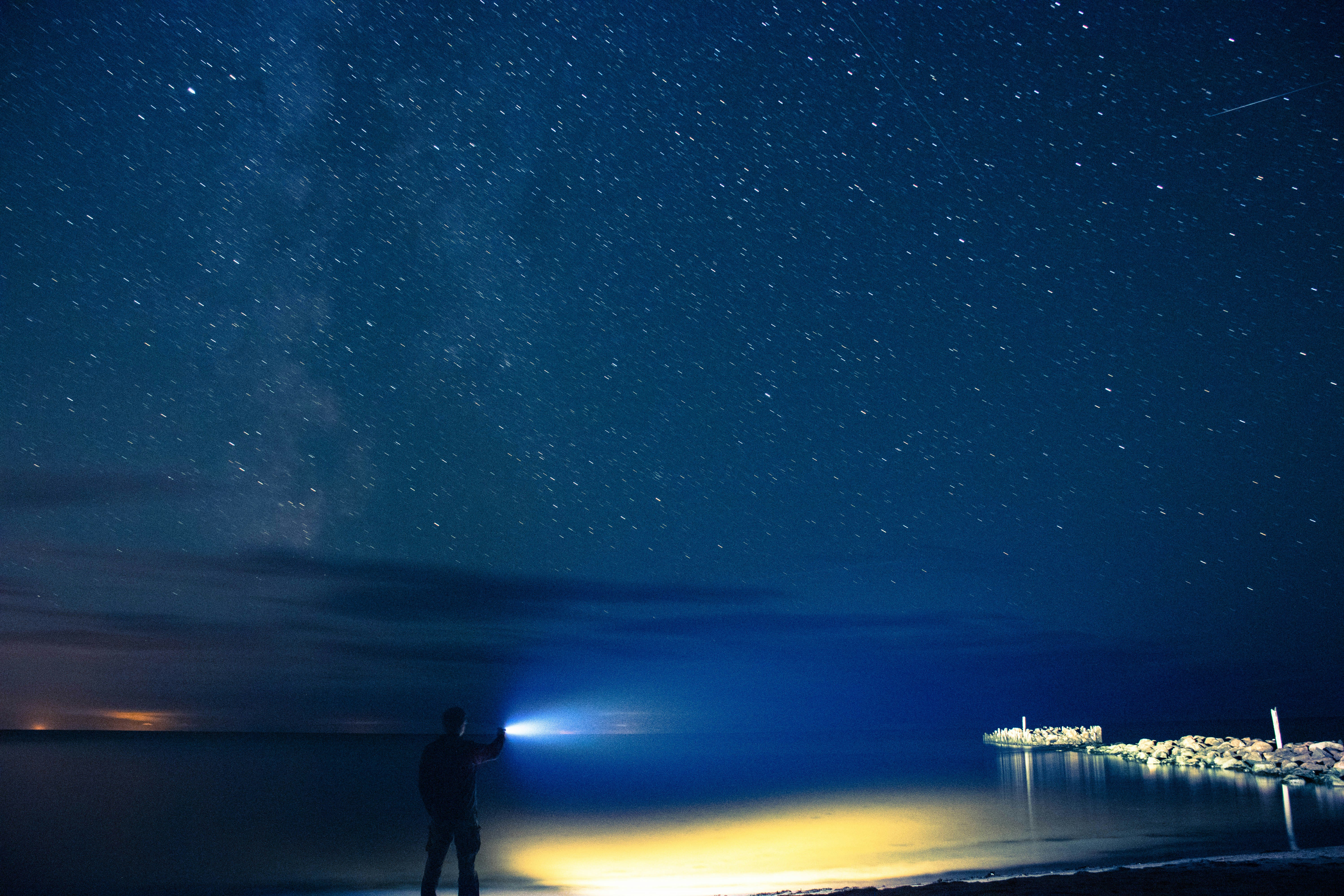 Man holding flashlight standing on seashore photo – Free Blue Image on ...
