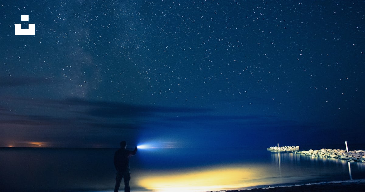 Man holding flashlight standing on seashore photo – Free Blue Image on ...