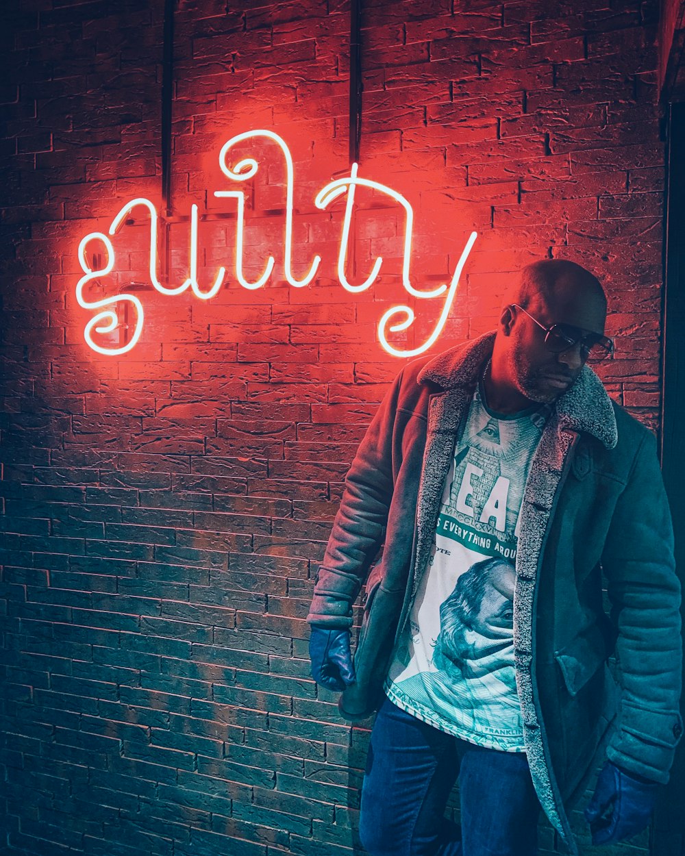 man wearing jacket standing beside neon light signage