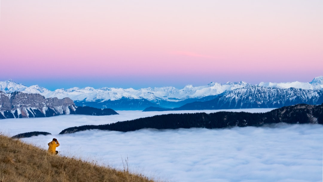 person sitting on high ground facing white clouds during daytime