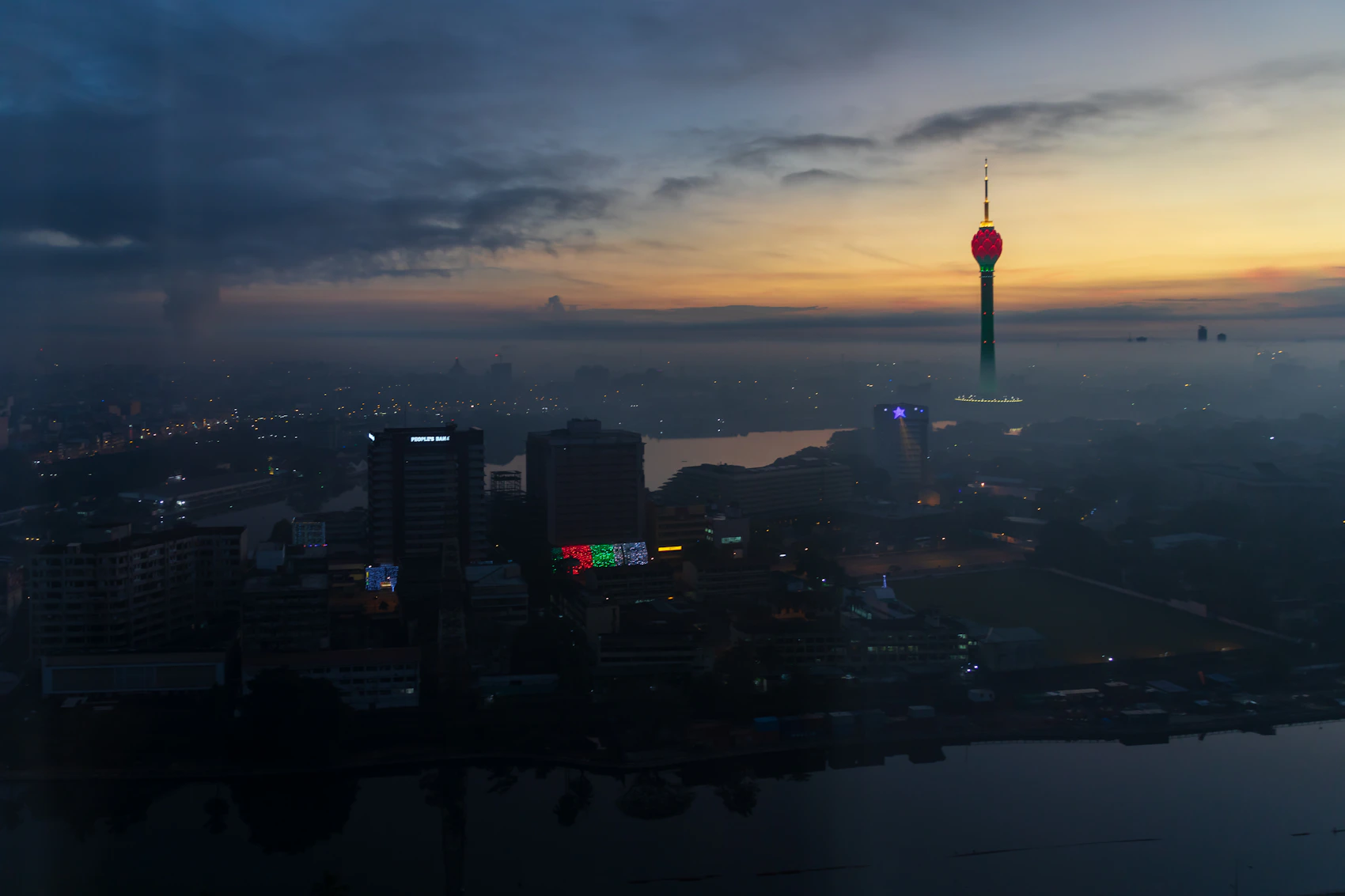 Colombo's Lotus Tower and city lights at dusk beneath rain-heavy clouds