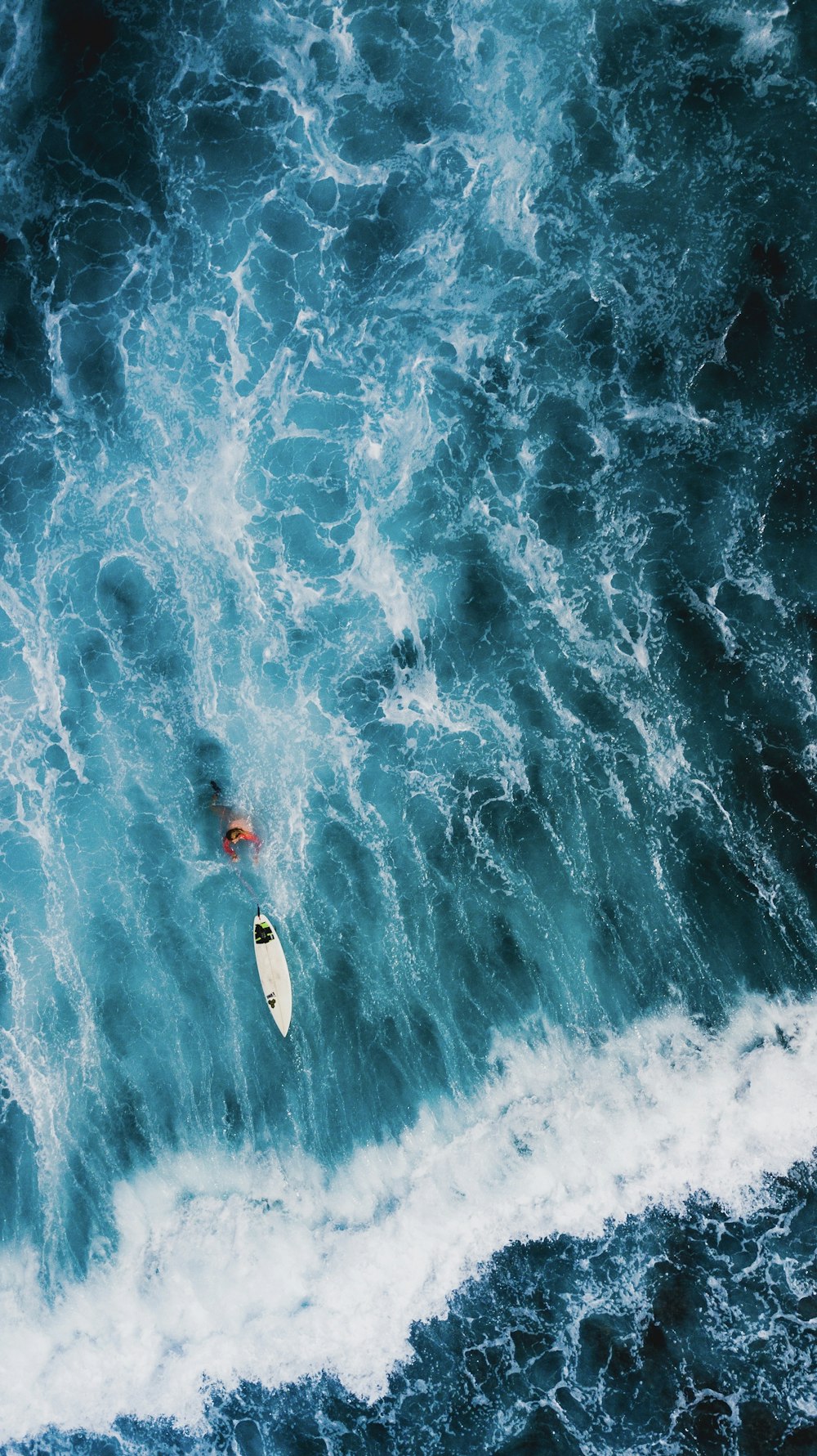 Luftaufnahme von Person und Surfbrett am Strand