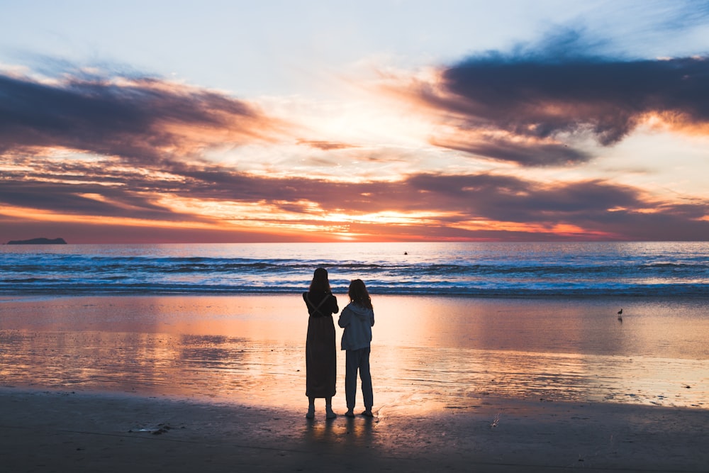 woman and girl standing on seashore