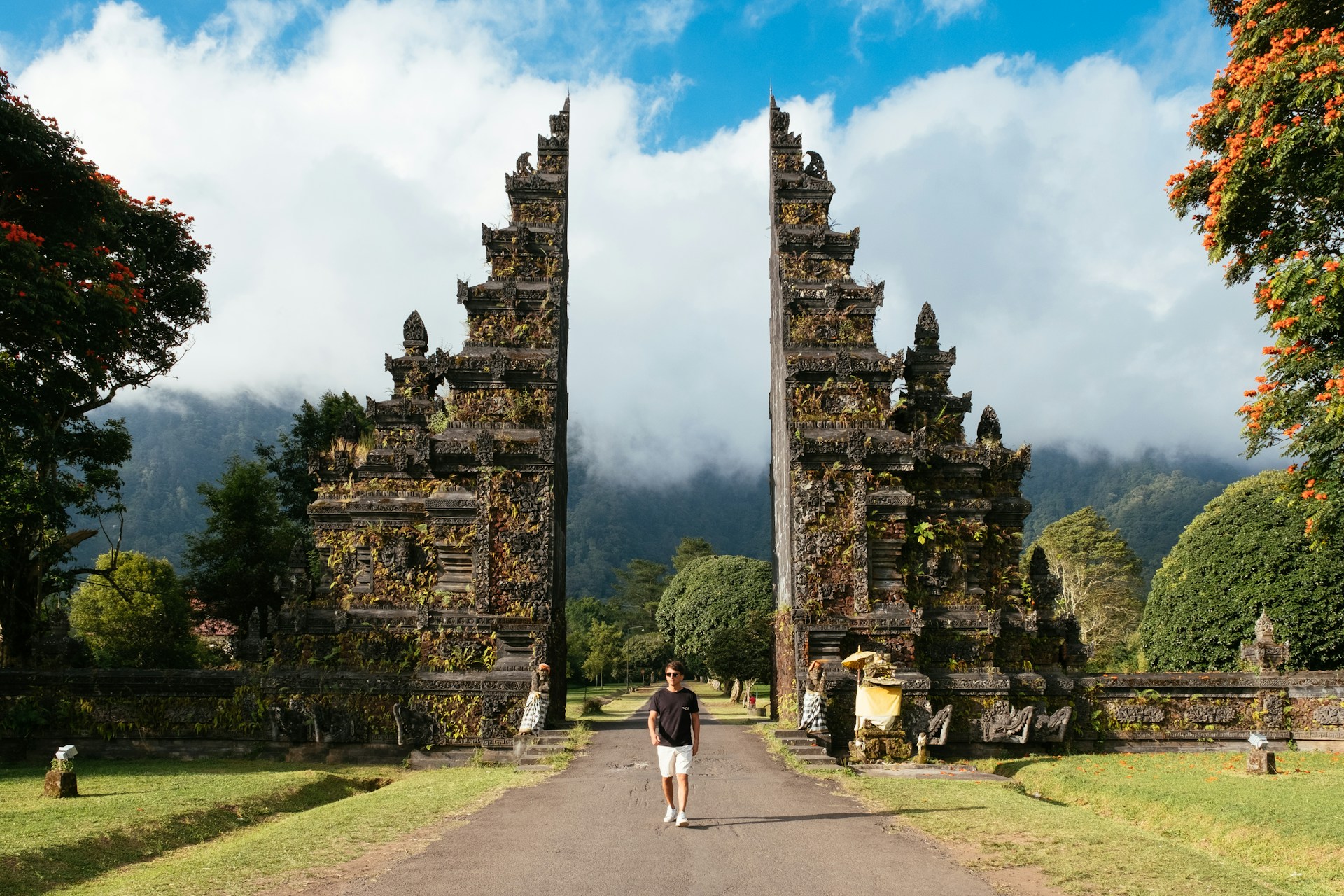 man walking between building under white clouds