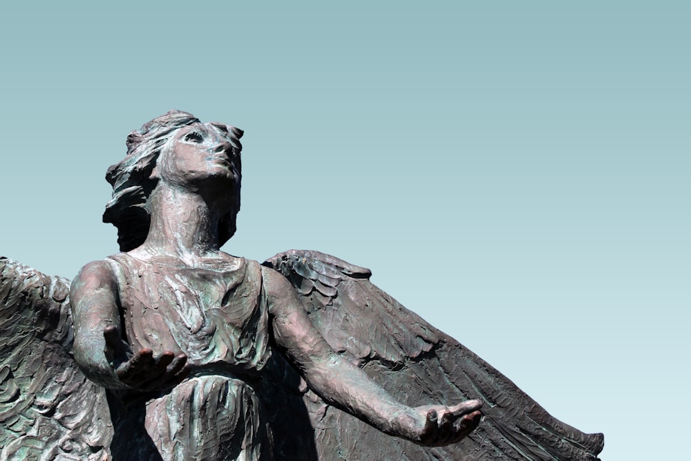 female angel looking up with both hands open statue