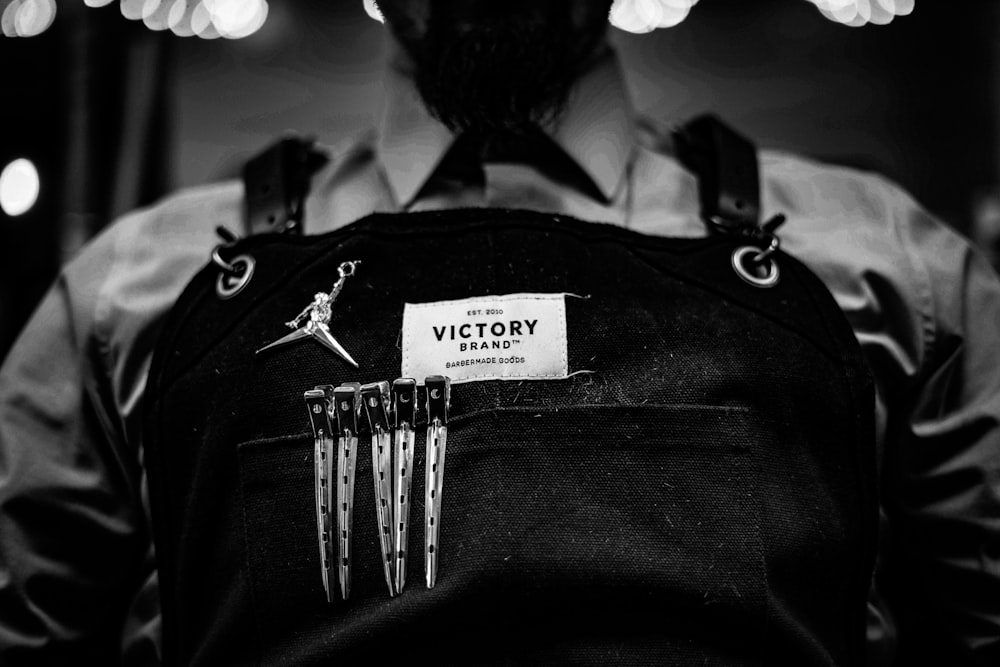 grayscale photography of person wearing black salon apron