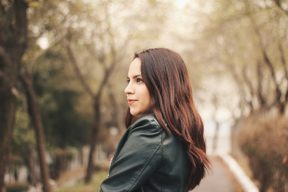 woman wearing black jacket standing beside tree