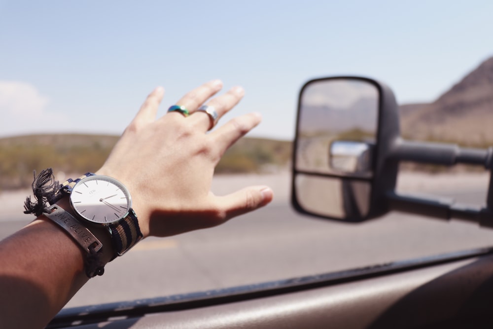 Person mit der linken Hand tagsüber aus dem Fahrzeugfenster