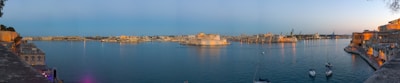 A panoramic view of Naples harbor at sunset with boats and historic buildings